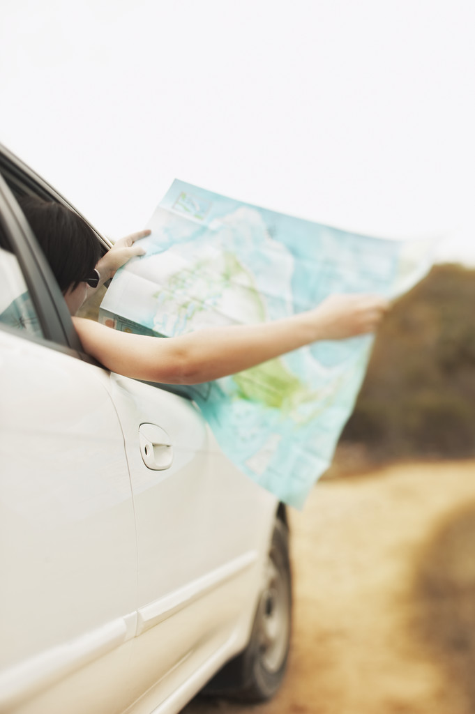 woman holding map out of car window