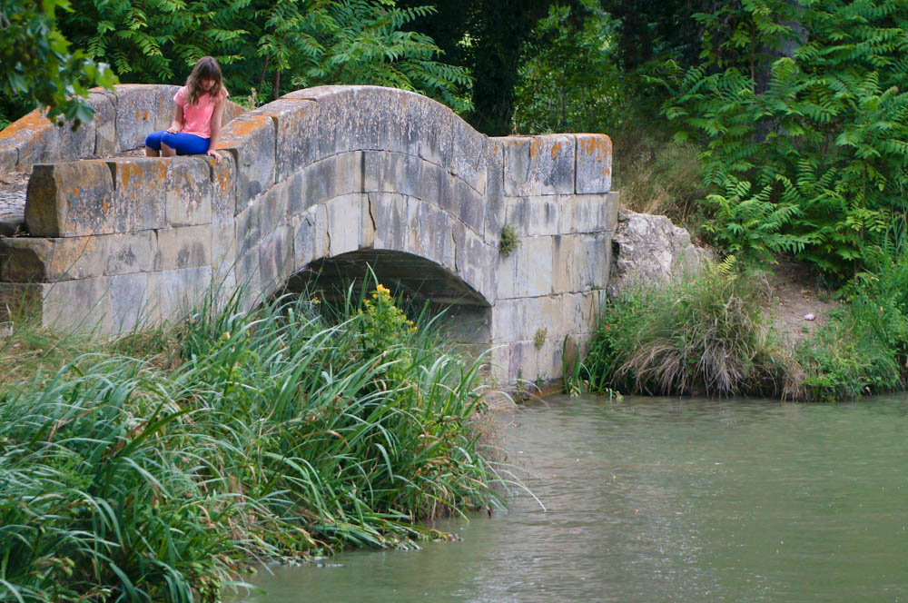 girl sitting on bridge on canal du midi in homps france