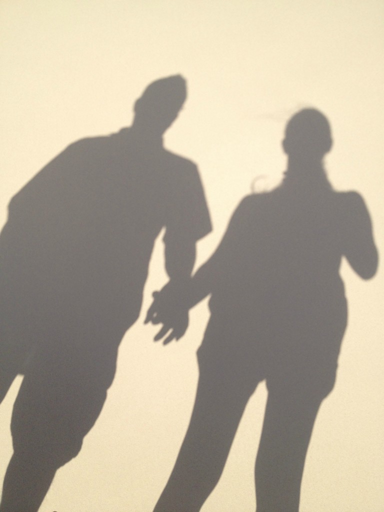 a shadow of a couple holding hands on a beach