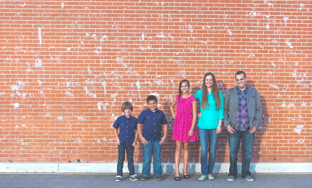 Family photo in front of an orange brick wall.