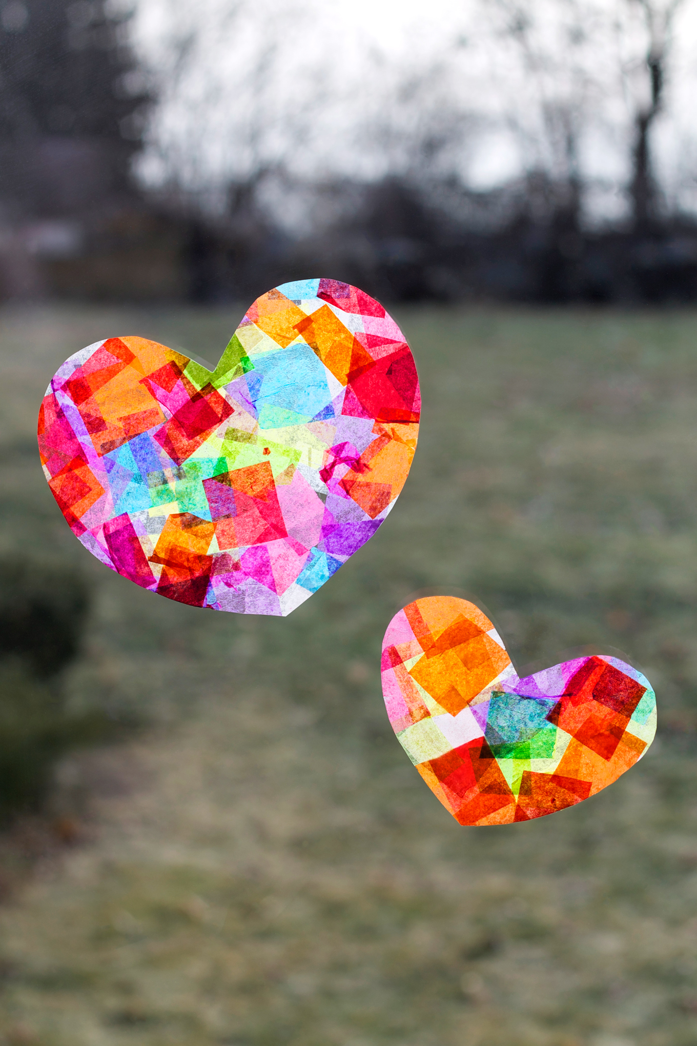 two hearts on a window made with colored tissue paper squares