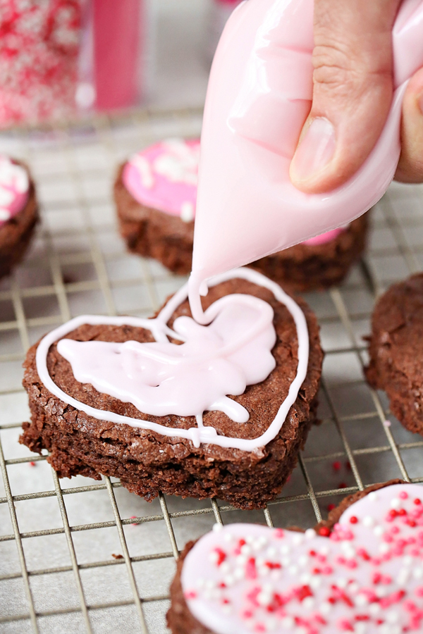 frosting a heart shaped brownie with a bag of pink icing