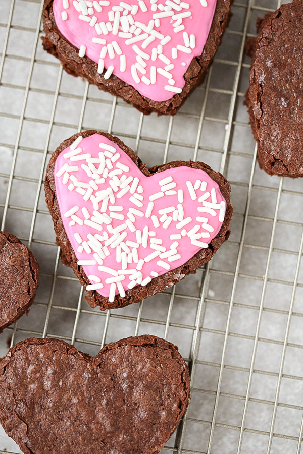 A tray of Heart Shaped Brownies frosted with pink icing and white sprinkles