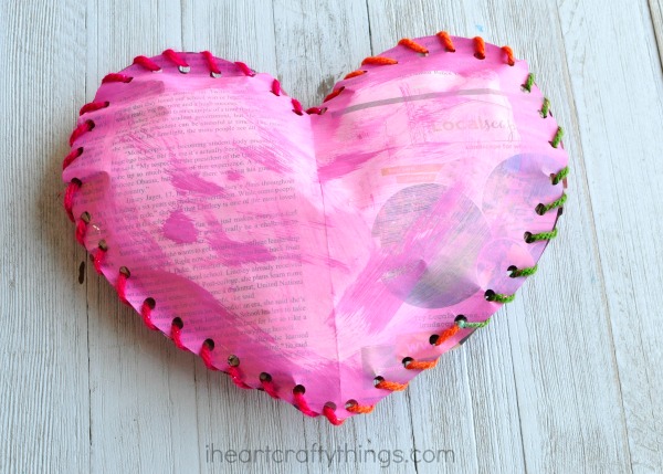 a pink heart made from old newspaper and yarn