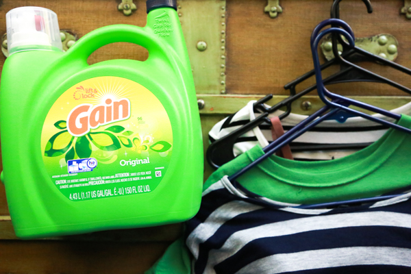 clothes on hangers laid on a vintage box with Gain laundry detergent