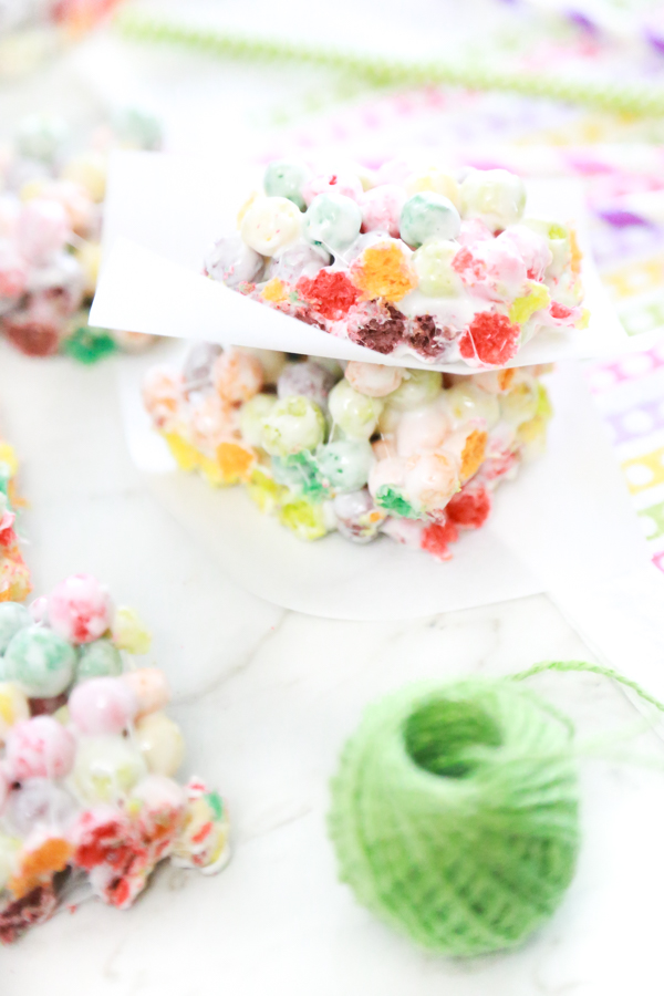 rainbow marshmallow treats stacked with a spool of green ribbon to the side