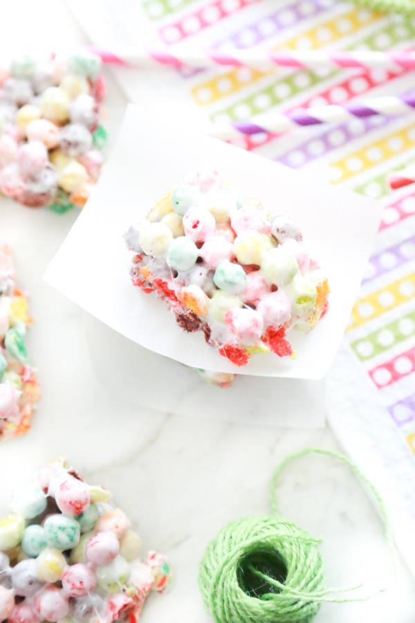 rainbow marshmallow treats on a white background with colorful napkin and green twine