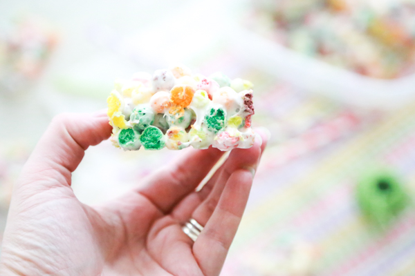 someone holding a rainbow marshmallow treat in their hand