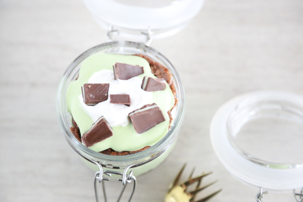 a glass jar filled with layer of brownie, cool whip and pudding to make a St. Patrick's Day Parfait