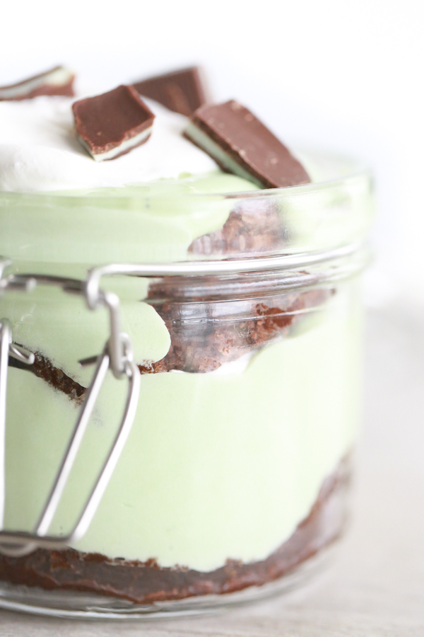 a glass jar filled with layer of brownie, cool whip and pudding to make a St. Patrick's Day Parfait