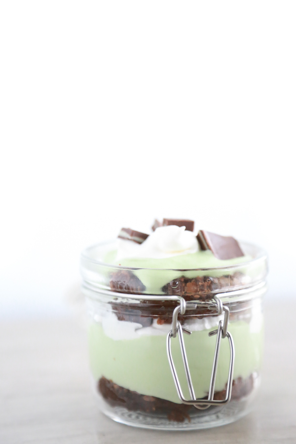 a glass jar filled with layer of brownie, cool whip and pudding to make a St. Patrick's Day Parfait