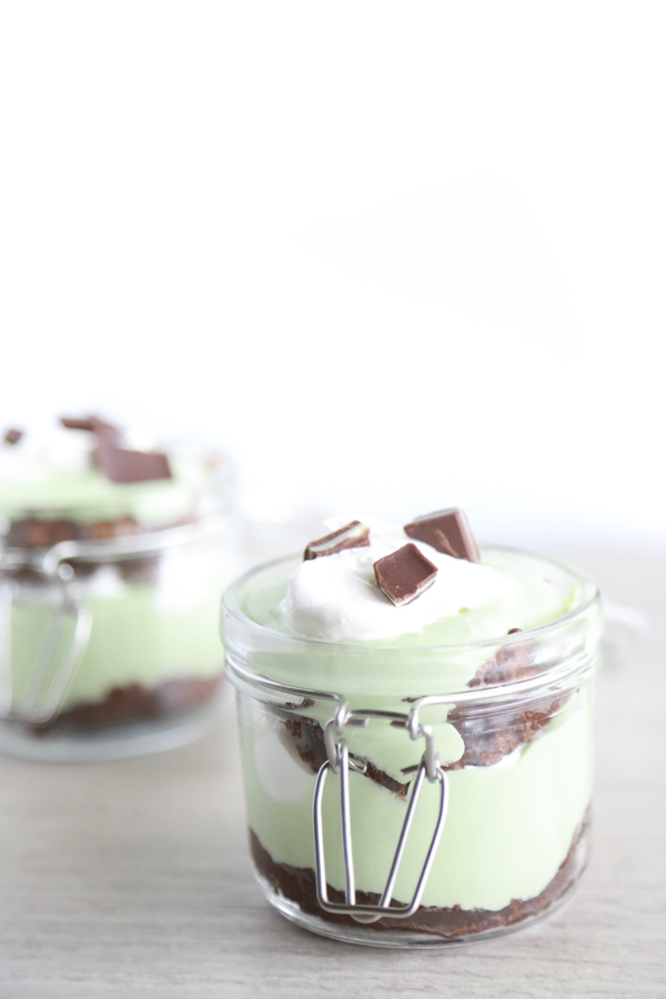 a glass jar filled with layer of brownie, cool whip and pudding to make a St. Patrick's Day Parfait