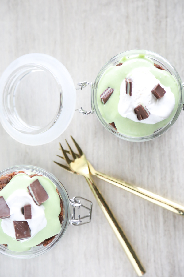 a glass jar filled with layer of brownie, cool whip and pudding to make a St. Patrick's Day Parfait