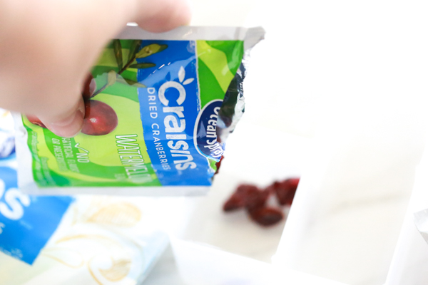 Pouring a bag of Ocean Spray Craisins into an on-the-go snack box