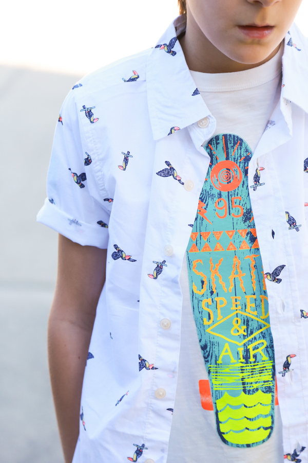 A little boy wearing a surf board shirt with a white button-up on top with toucans -perfect spring styles at oshkosh b'gosh