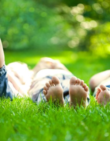 Group of happy children lying on green grass outdoors in spring park