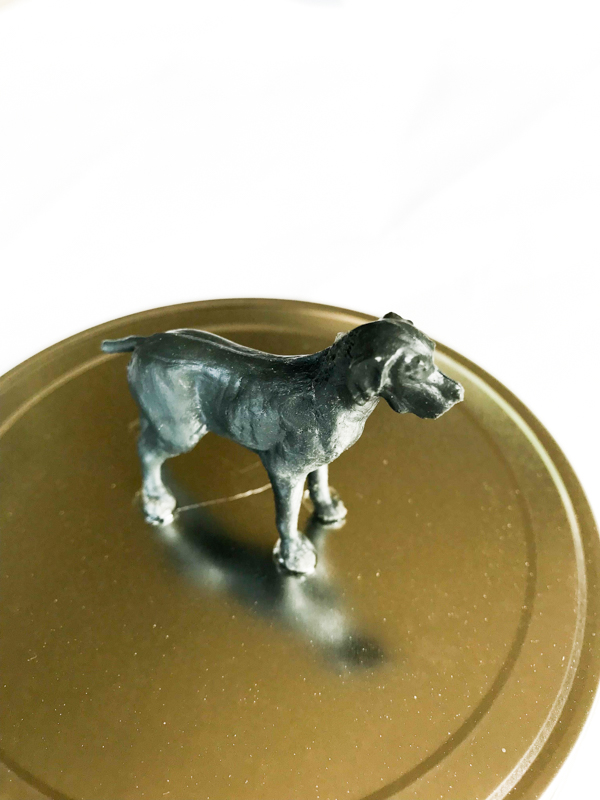 a glass jar lid with a dog figure glued on top to make a homemade dog treat jar