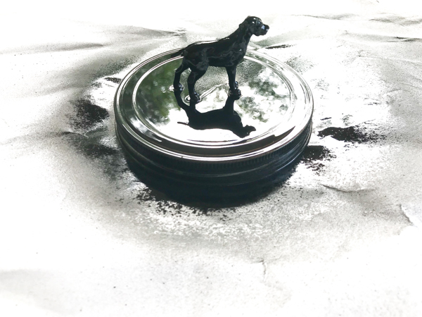 a glass lid with a dog figure glued on top and spray painted black to make the lid of a homemade dog treat jar