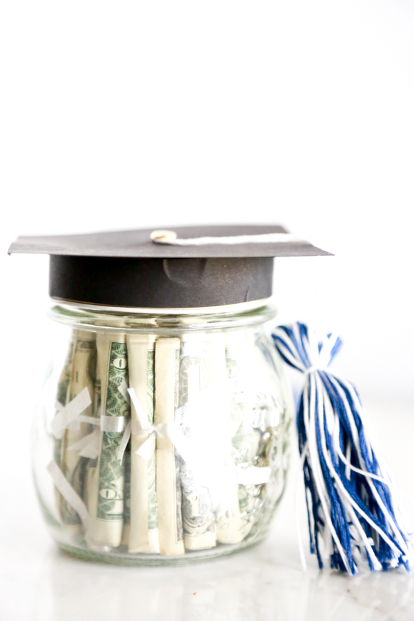 Surprise the deserving graduate with this adorable Mason Jar Graduation Hat Gift Idea filled with dollar bill diplomas.